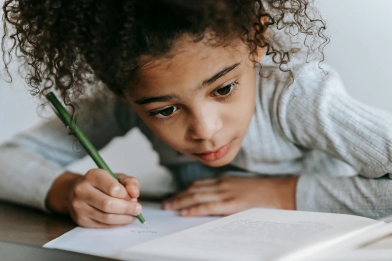 a little girl is writing on a piece of paper, pexels contest winner, curled up on a book, pokimane, riyahd cassiem, informative texts