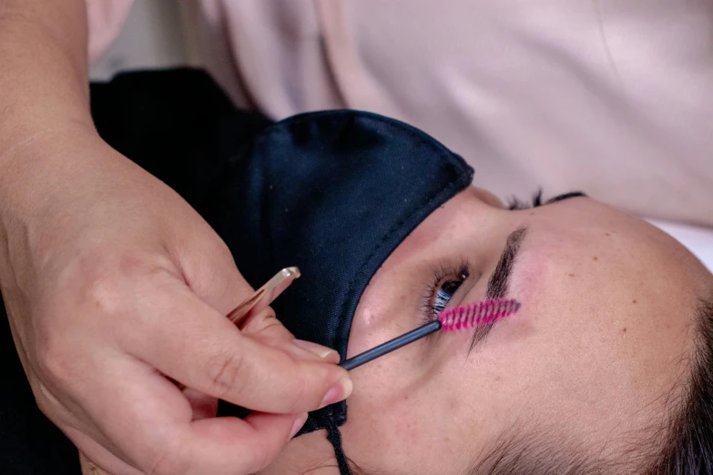 a close up of a person putting mascara on a person's eye, by Julia Pishtar, hurufiyya, thumbnail, wearing mask, a high angle shot, put on a mannequin