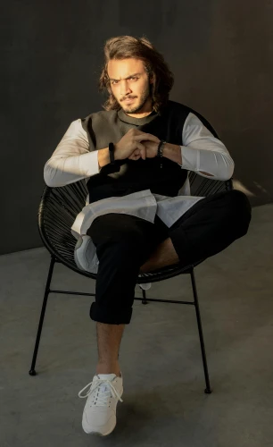 a man with long hair sitting in a chair, inspired by Bikash Bhattacharjee, trending on pexels, portrait full body, cinematic outfit photo, promotional image, profile image