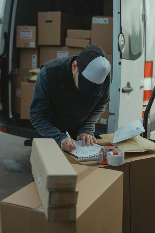 a man writing on a piece of paper in front of a van, packaging, inspect in inventory image, thumbnail, cinematic image