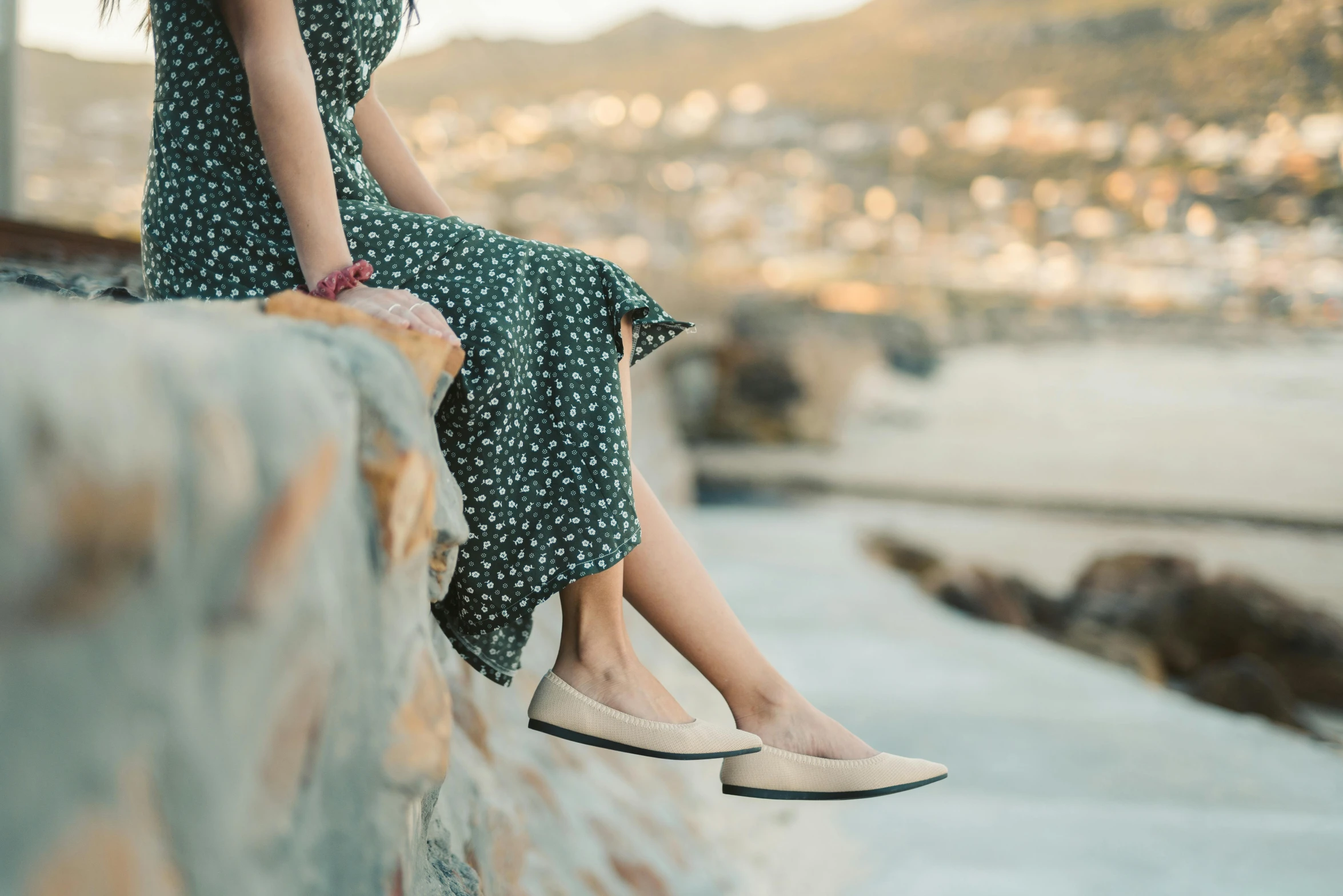 a woman sitting on top of a stone wall, a picture, by Carey Morris, trending on pexels, arabesque, silk shoes, sandy beige, flat, lightly dressed