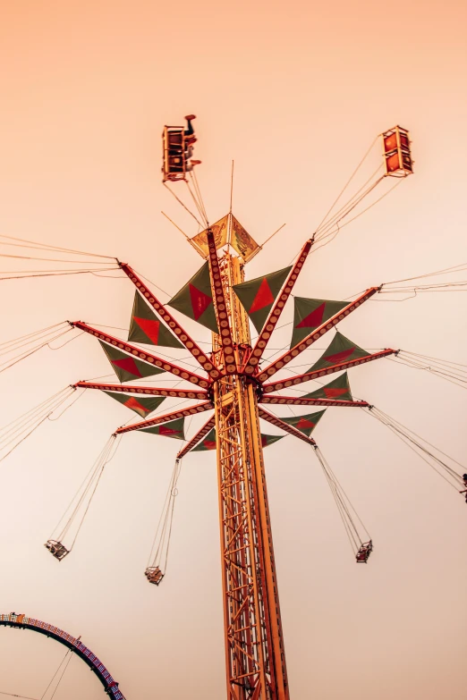 a carnival ride with a ferris wheel in the foreground, pexels contest winner, faded red and yelow, parachutes, tower, brown