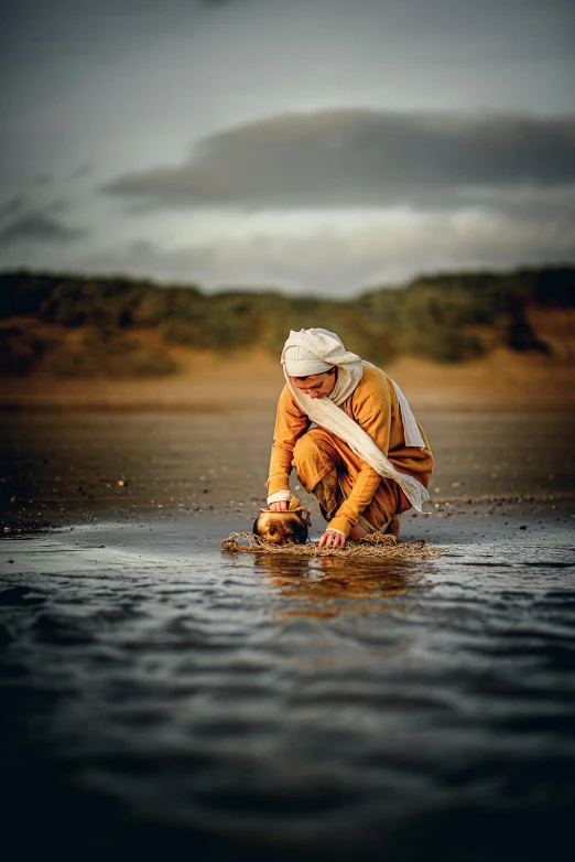 a person kneeling in a body of water, inspired by Steve McCurry, unsplash, wearing a turban, sorcerer of sand, working, ochre
