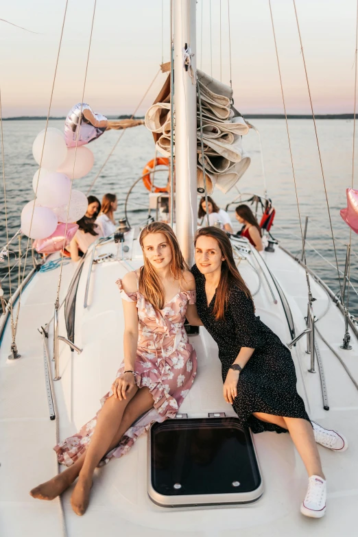 two women sitting on the bow of a sailboat, a picture, pexels contest winner, happening, birthday party, dasha taran, flowers, party balloons