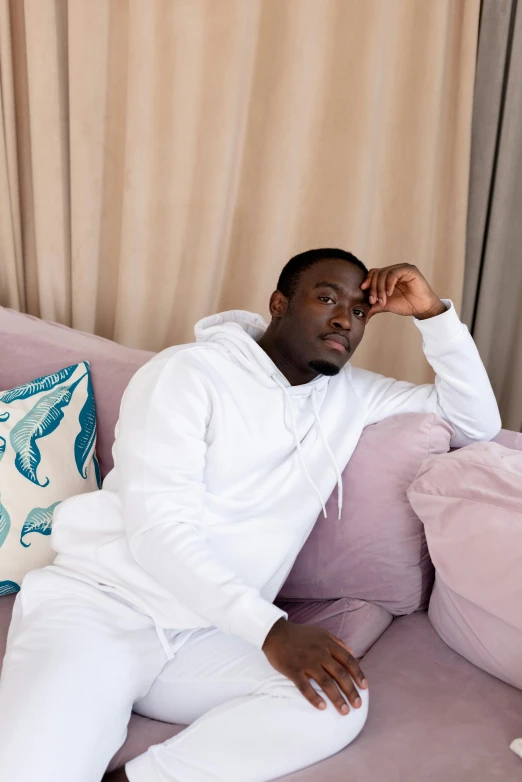 a man sitting on top of a pink couch, an album cover, inspired by Barthélemy Menn, pexels contest winner, happening, wearing white pajamas, jaylen brown, wearing a grey hooded sweatshirt, profile pic