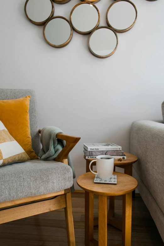 a living room filled with furniture and a mirror on the wall, inspired by Constantin Hansen, trending on unsplash, minimalism, two cups of coffee, light grey blue and golden, reading nook, medium close up shot