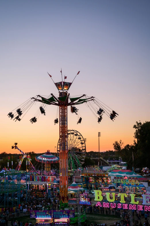 a carnival filled with lots of people and rides, during a sunset, profile image