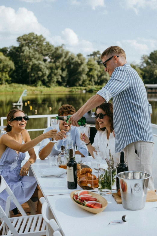 a group of people sitting around a table on a boat, river of wine, plating, drinking champagne, dutch style