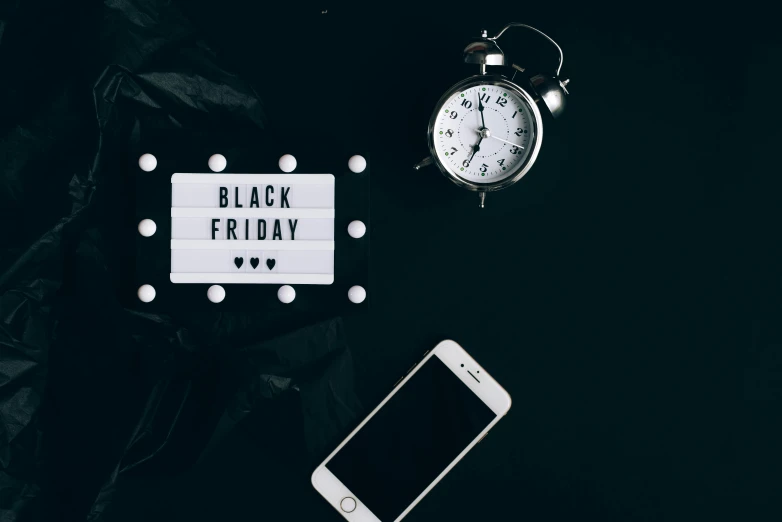 a cell phone sitting next to a black friday sign, a photo, by Julia Pishtar, trending on unsplash, hurufiyya, white moon and black background, miniature product photo, holiday vibe, background image