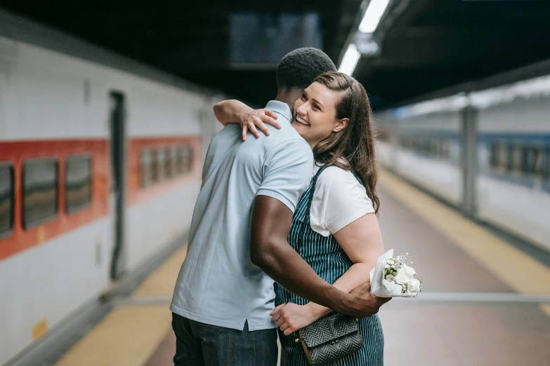 a man and a woman hugging in front of a train, pexels contest winner, happening, holding flowers, central station in sydney, diverse, reuniting