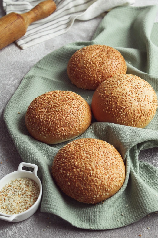 a couple of buns sitting on top of a green towel, sexy sesame seed buns, 6 pack, 4l, golden