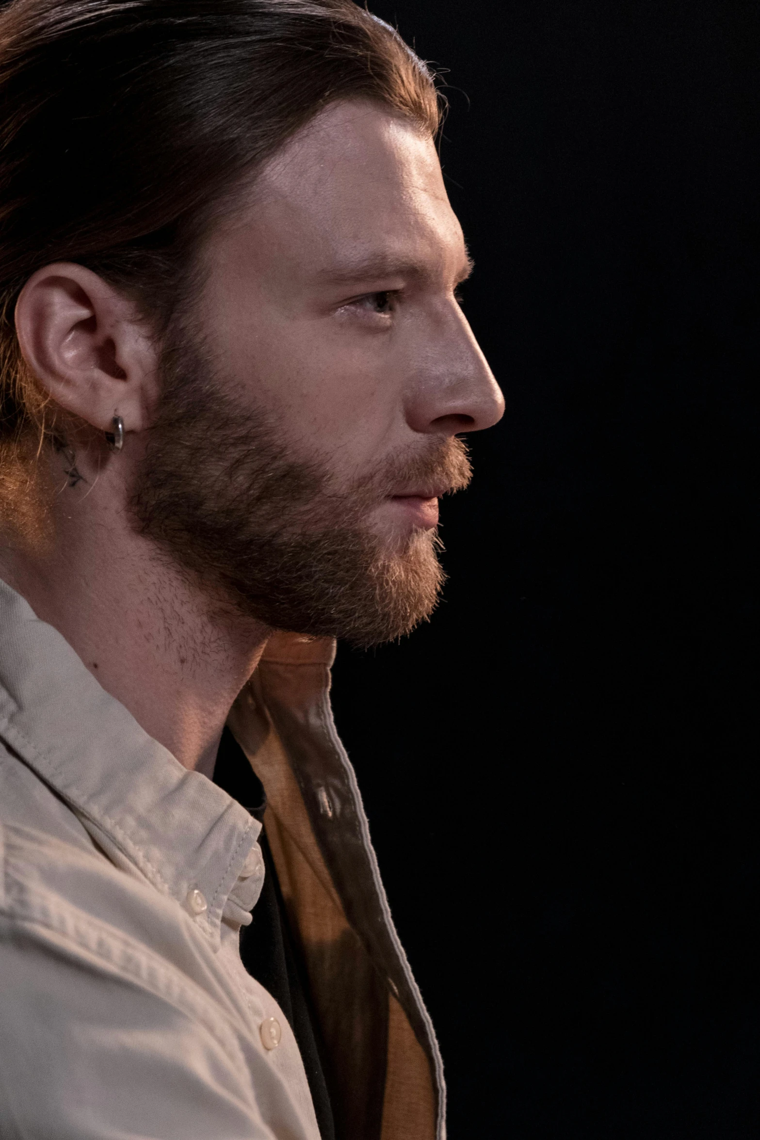 a man with a beard sitting in front of a microphone, chiseled jawline, ( ( theatrical ) ), aura jared and wires, side view close up of a gaunt