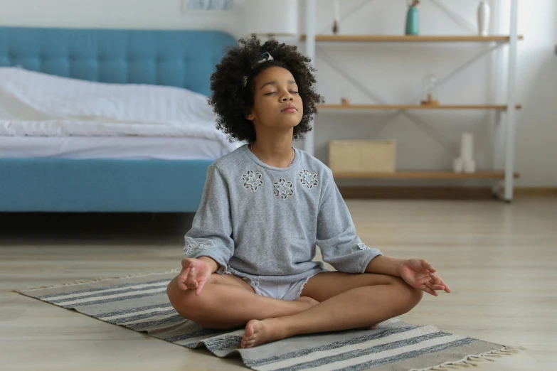 a little girl sitting in the middle of a yoga pose, pexels, hurufiyya, wearing a grey robe, sitting in bedroom, girl wearing uniform, photo of a black woman