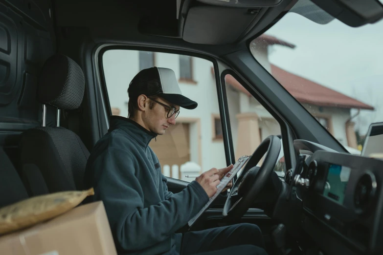 a man sitting in the driver's seat of a truck, pexels contest winner, writing on a clipboard, avatar image, medium distance shot, profile picture