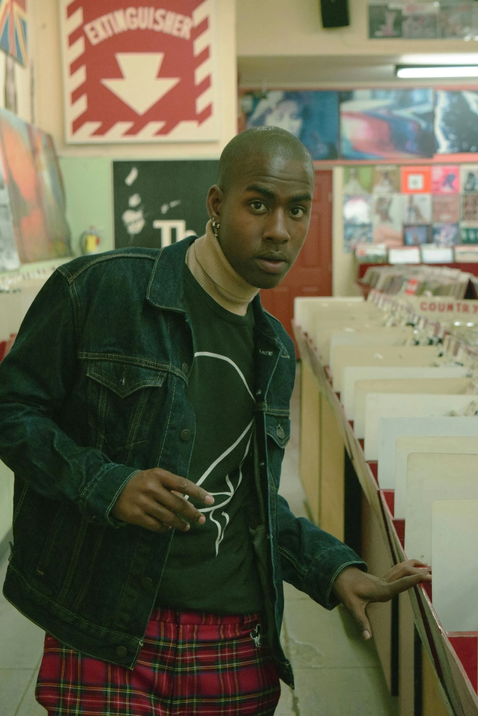 a man standing in a store holding a cell phone, an album cover, pexels, happening, dave chappelle, film still dnd movie, jean jacket, tense look