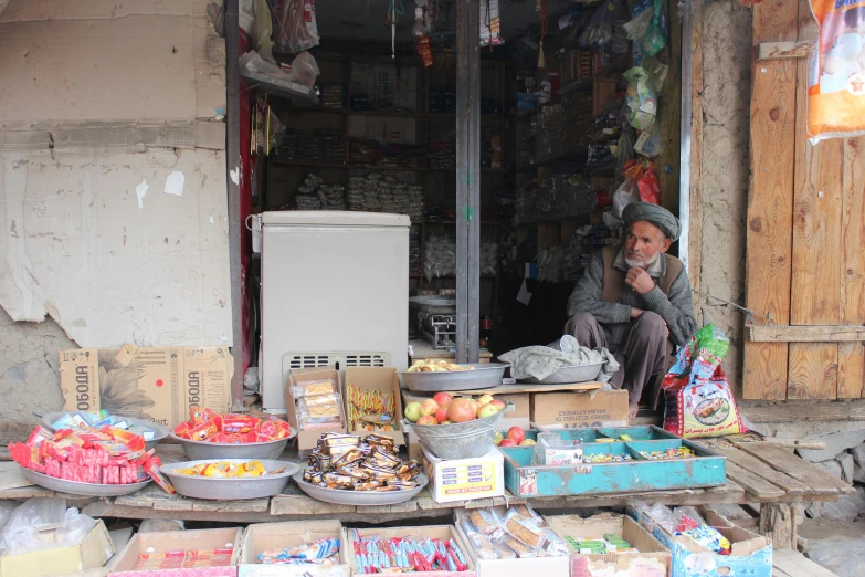 a man sitting in front of a store, pexels contest winner, les nabis, an afghan male type, snacks, 2 5 6 x 2 5 6 pixels, small in size