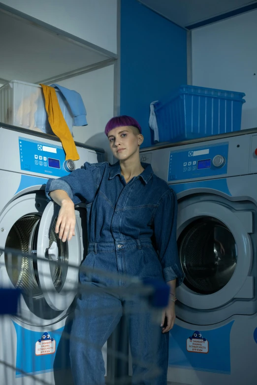 a man standing in front of a washing machine, inspired by Elsa Bleda, pexels contest winner, hyperrealism, short blue haired woman, wearing plumber uniform, production still, blue and violet