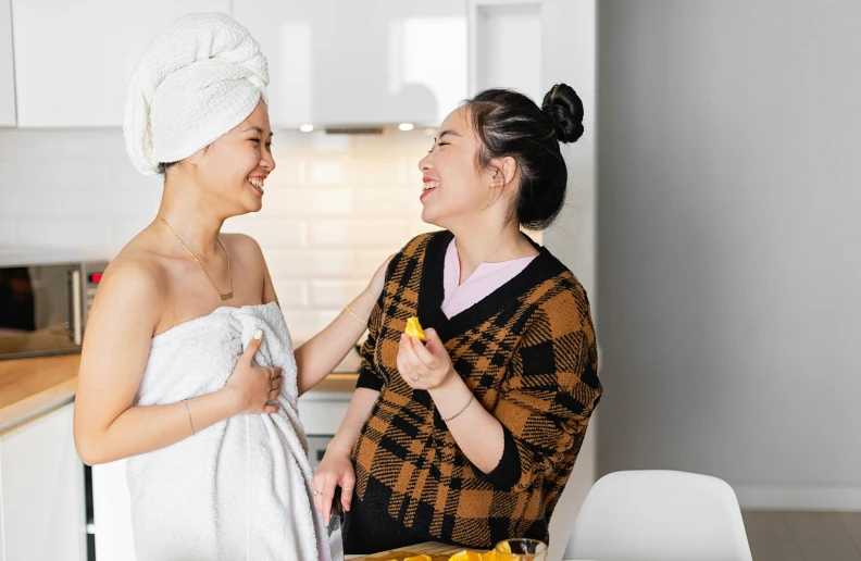 a couple of women standing next to each other in a kitchen, pexels contest winner, happening, wearing a towel, asian features, nursing, smiling at each other