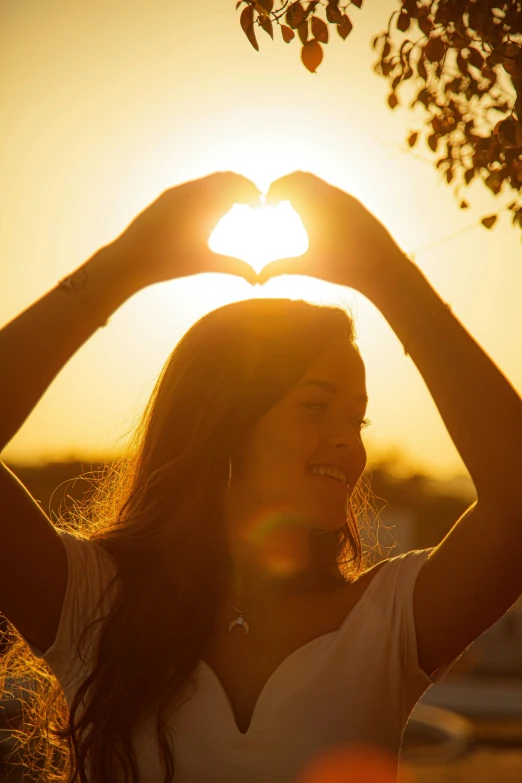 a woman making a heart shape with her hands, pexels contest winner, sun flairs, profile pic, front lit, suns