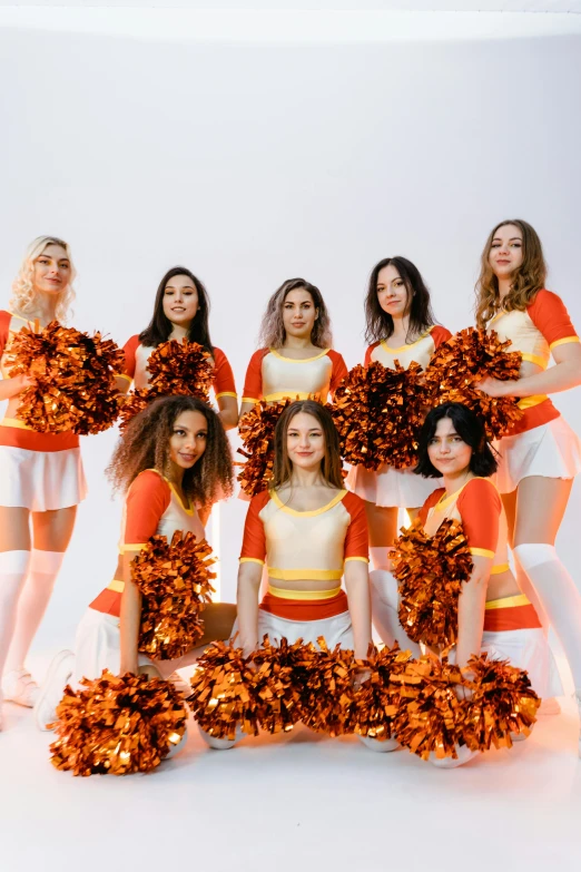 a group of cheerleaders posing for a picture, an album cover, pexels contest winner, studio orange, ukraine. professional photo, leafs, orange and white color scheme