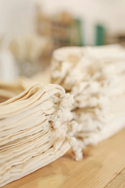 a stack of papers sitting on top of a wooden table, by Helen Stevenson, process art, steamed buns, ecru cloth, close up details, pasta