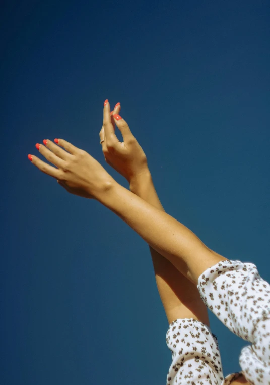 a woman reaching up to catch a frisbee, unsplash, aestheticism, cloudless blue sky, painted nails, porcelain skin ”, in style of joel meyerowitz