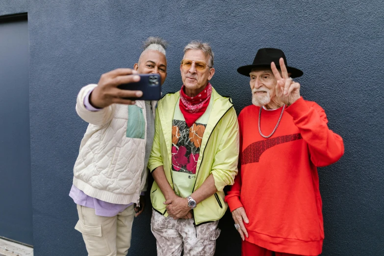 a group of three men standing next to each other, a photo, by Winona Nelson, colourful clothing, holding it out to the camera, elderly, influencers