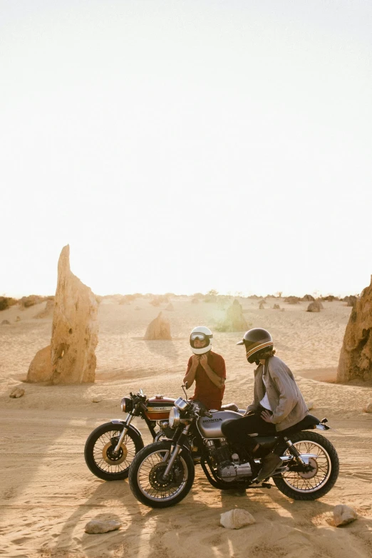 a couple of people riding on the back of a motorcycle, by Lee Loughridge, unsplash contest winner, conceptual art, sandstone, summer setting, golden glow, helmet off