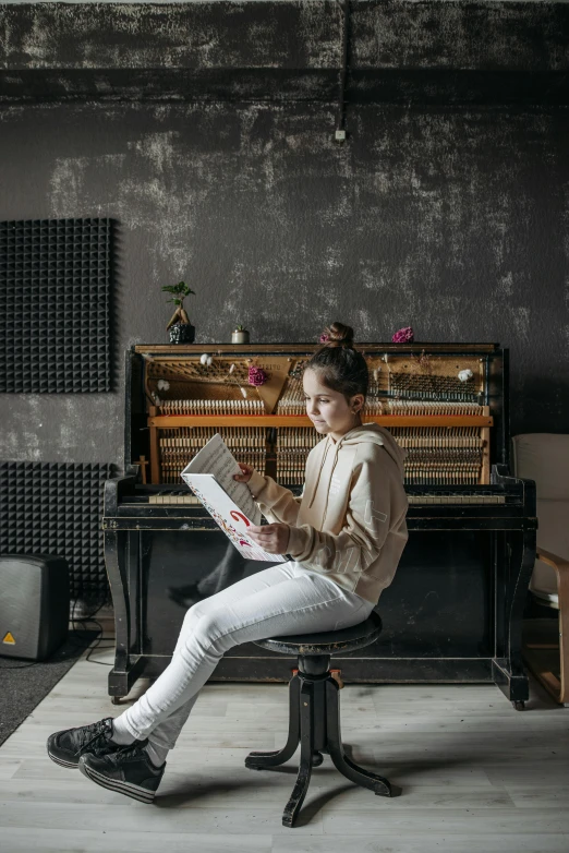 a woman sitting on a chair reading a book, an album cover, pexels contest winner, real pianos, little kid, teenage girl, sitting at a control center