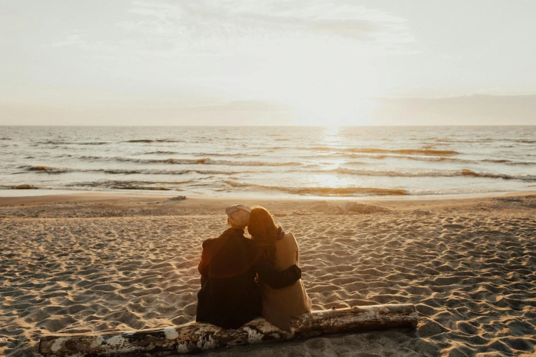 two people sitting on a blanket on the beach, by Julia Pishtar, pexels contest winner, romanticism, warm glow, lesbian embrace, looking onto the horizon, manly