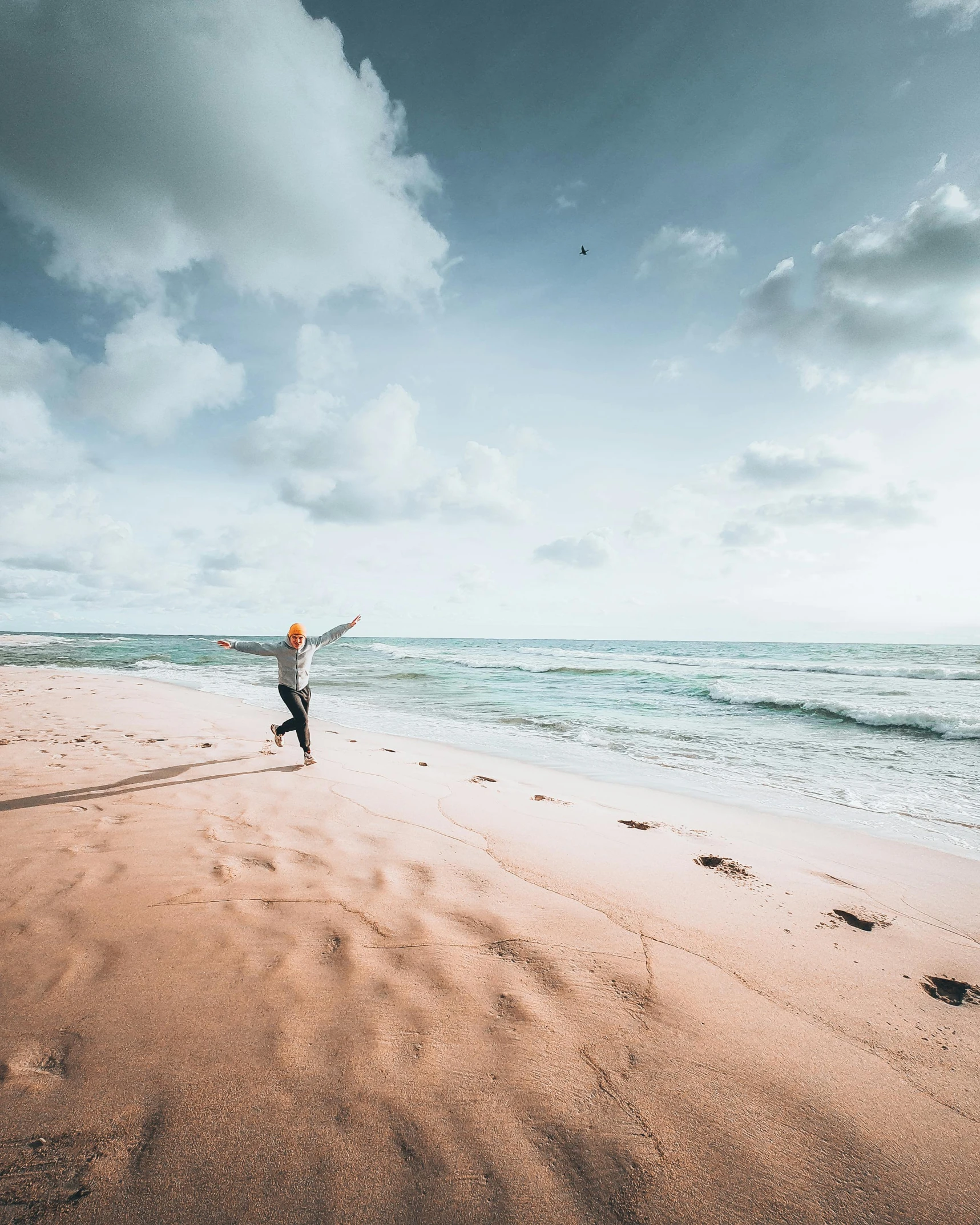 a man flying a kite on top of a sandy beach, by Sebastian Spreng, pexels contest winner, pink hues, pose(arms up + happy), photo of the middle of the ocean, red sand