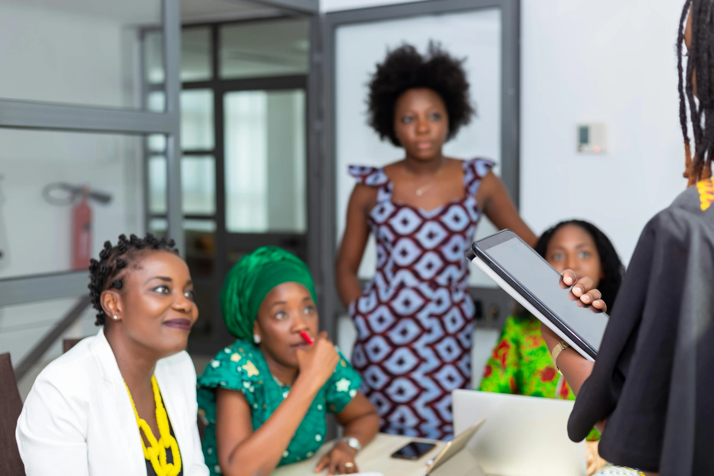 a group of women sitting around a table, by Ingrida Kadaka, pexels contest winner, giving a speech, afro tech, customers, a person standing in front of a