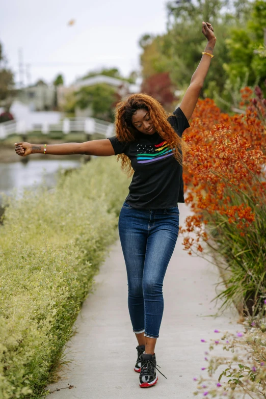 a woman riding a skateboard down a sidewalk, unsplash, renaissance, pose(arms up + happy), jeans and t shirt, gold black and rainbow colors, standing in a pond