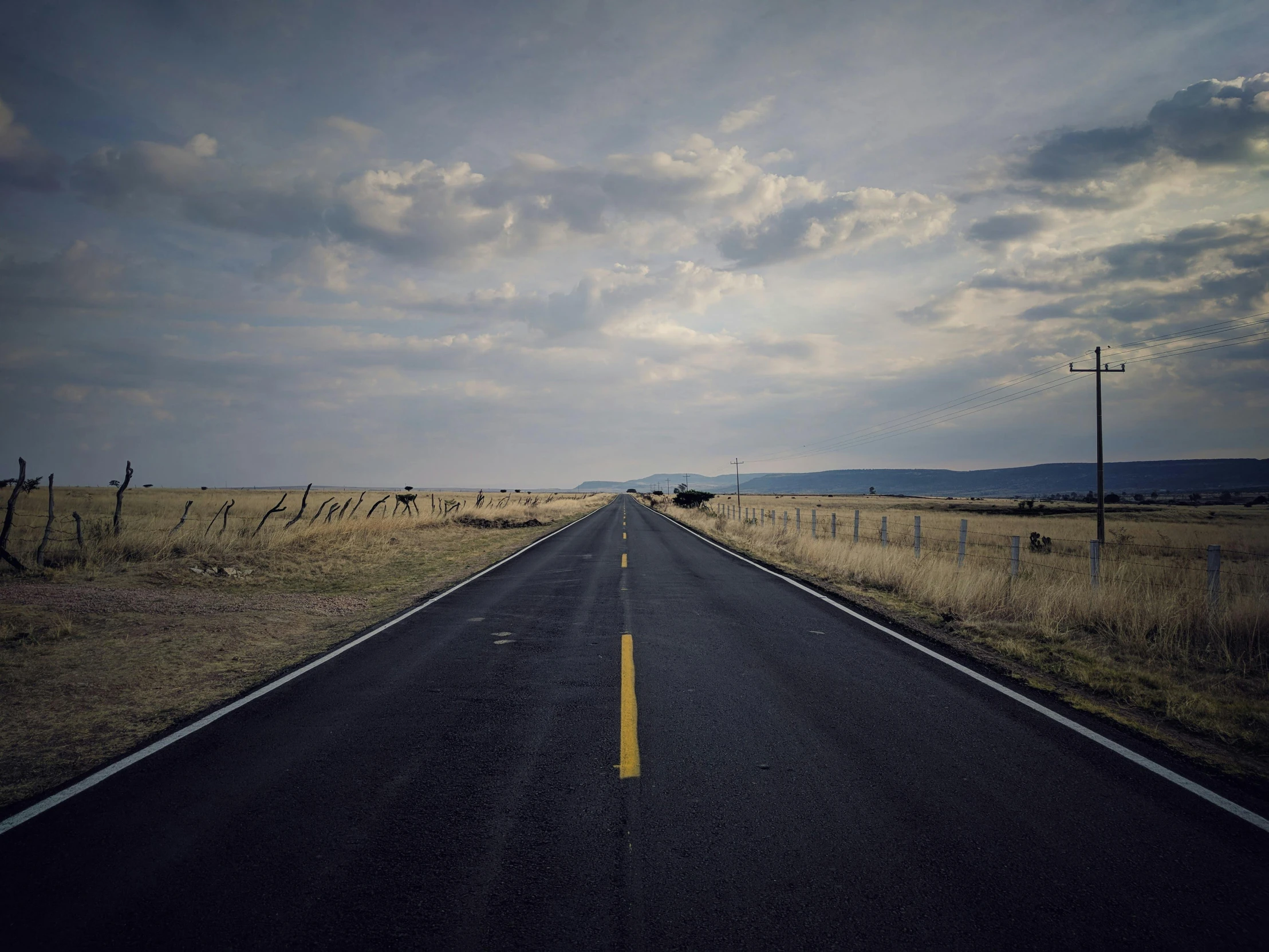 a long empty road in the middle of a field, an album cover, by Pablo Rey, unsplash, annie liebowitz, photorealist, ignant, new mexico