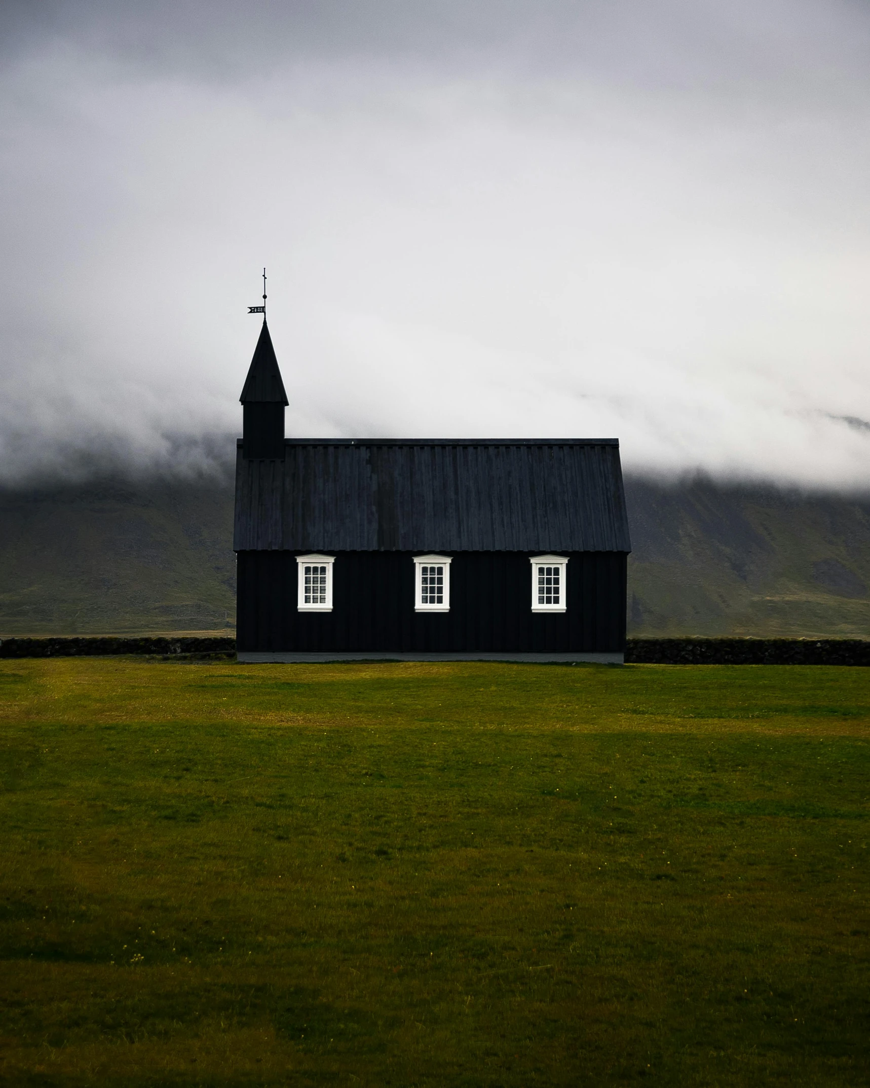 a black church sitting on top of a lush green field, pexels contest winner, but minimalist, highlands, storm outside, a quaint