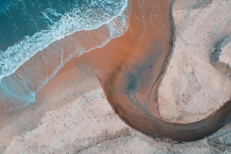 a river running through a sandy beach next to the ocean, unsplash contest winner, land art, flowing salmon-colored silk, “ iron bark, helicopter view, introspective meandering