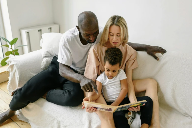 a woman and two children sitting on a couch reading a book, a cartoon, by Adam Marczyński, pexels contest winner, black man, a handsome, gif, husband wife and son