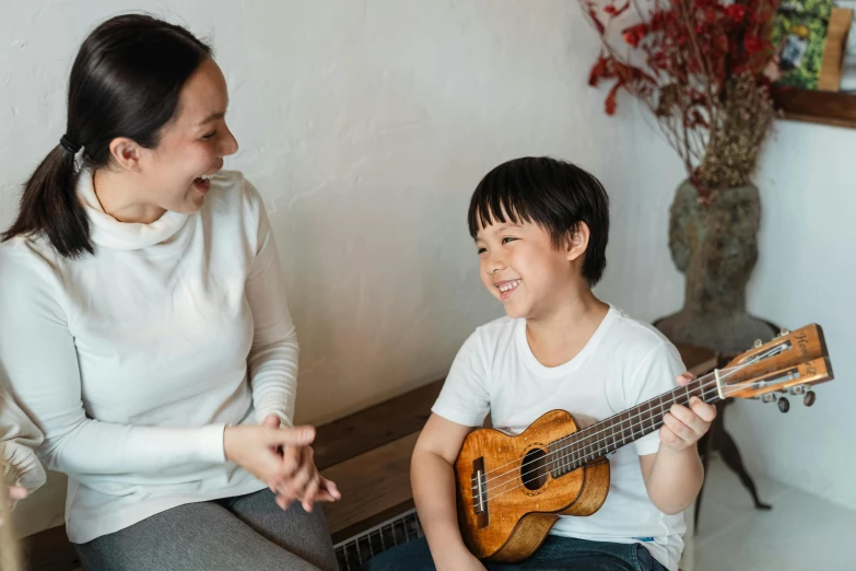 a woman sitting next to a young boy holding a guitar, pexels contest winner, shin hanga, nerdy music teacher with phd, earing a shirt laughing, ukulele, youtube thumbnail