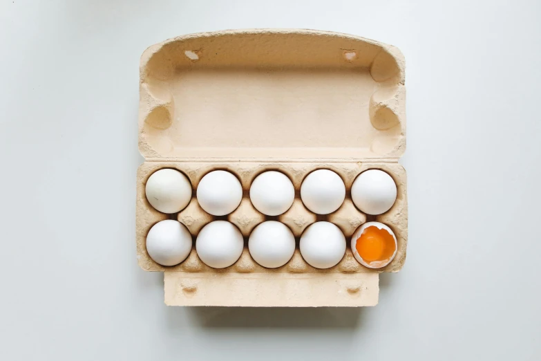 a carton filled with eggs sitting on top of a table, unsplash, dau-al-set, white and orange, ffffound, a wooden, professional product photo