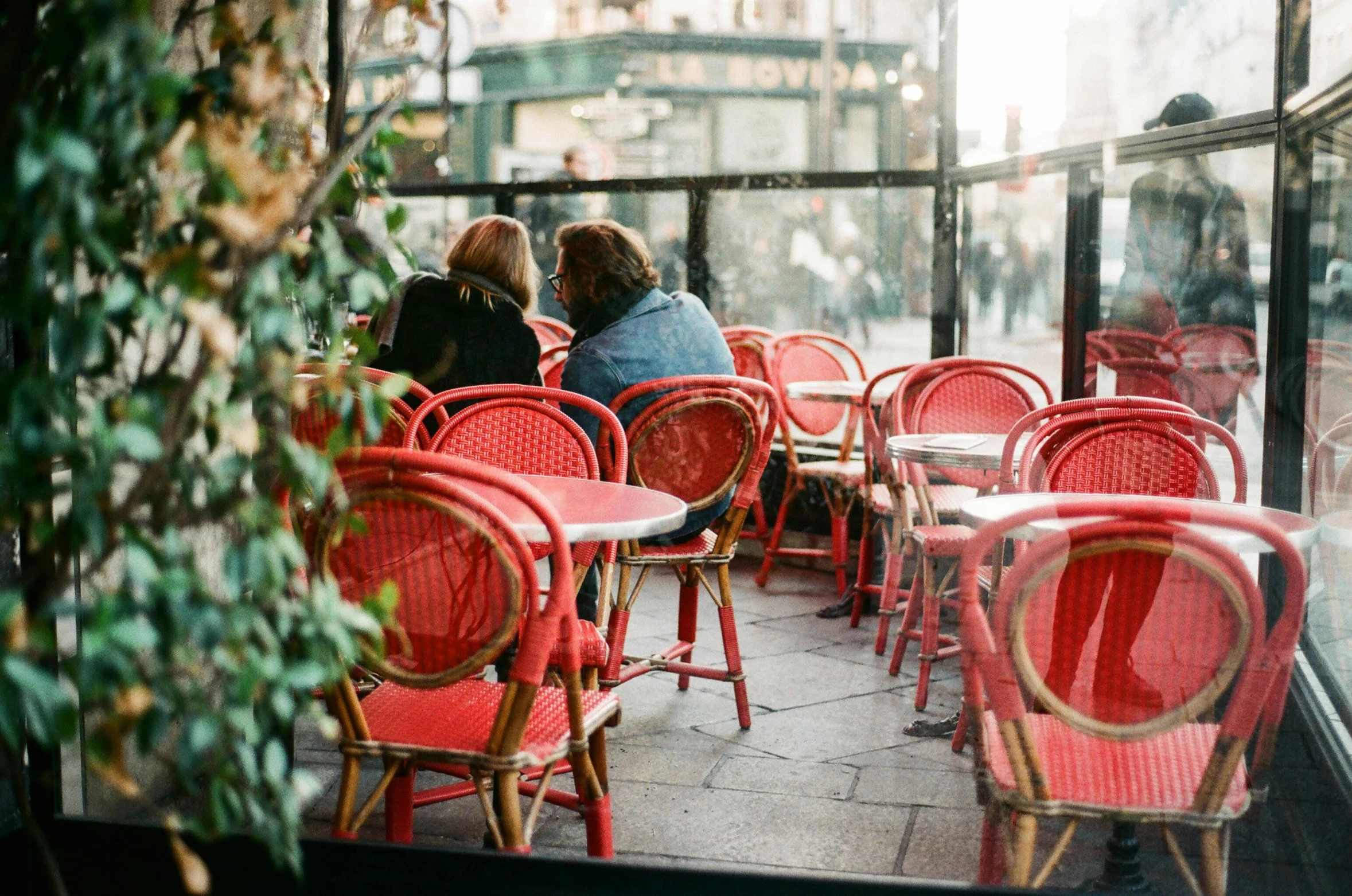 a group of people sitting at tables in a restaurant, by Julia Pishtar, trending on unsplash, art nouveau, wearing red clothes, un restaurant avec une terrasse, french provincial furniture, french kiss