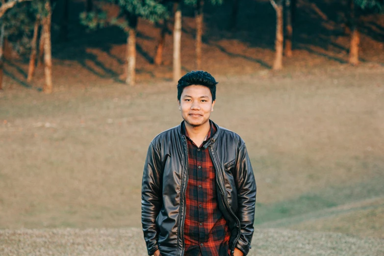 a man in a leather jacket standing in a field, pexels contest winner, hurufiyya, assamese aesthetic, avatar image, clean shaven, good lighted photo