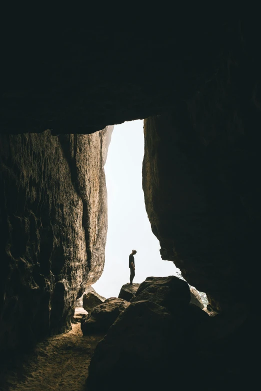 a person standing at the end of a cave, pexels contest winner, large overhangs, tiny person watching, rectangle, silhouetted