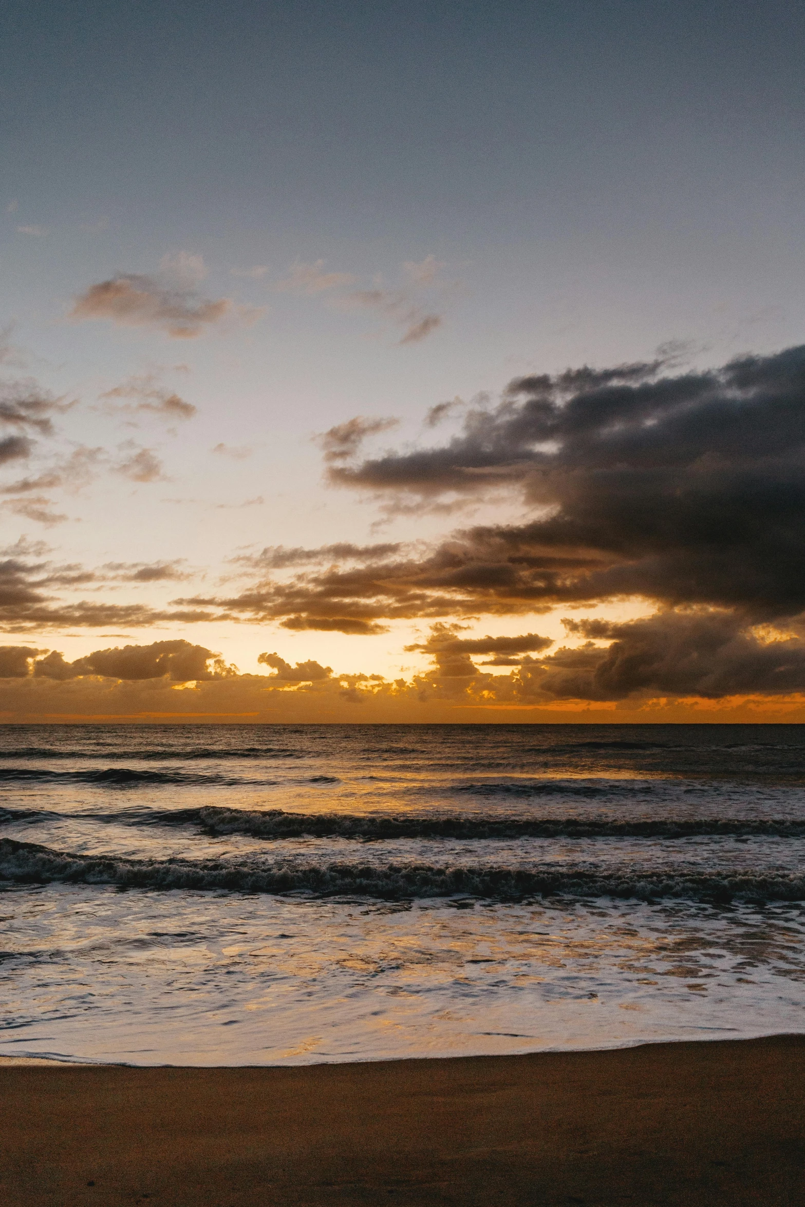 a man riding a surfboard on top of a sandy beach, inspired by Edwin Deakin, unsplash, minimalism, sunset clouds, 8 k wide shot, new zealand, today\'s featured photograph 4k