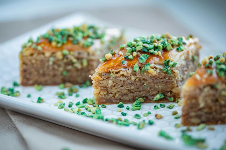 a close up of a piece of food on a plate, hurufiyya, square, 3 - piece, festive, pastries