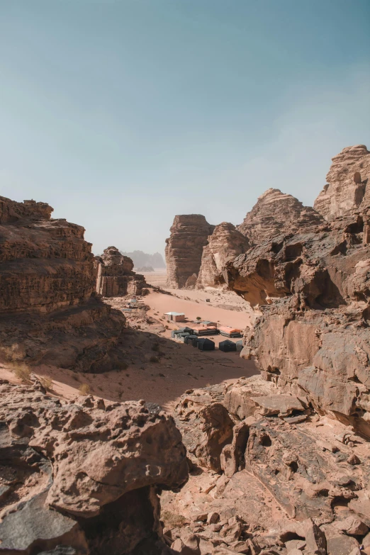 a large rock formation in the middle of a desert, les nabis, cars parked underneath, canyons, sunfaded, high-angle