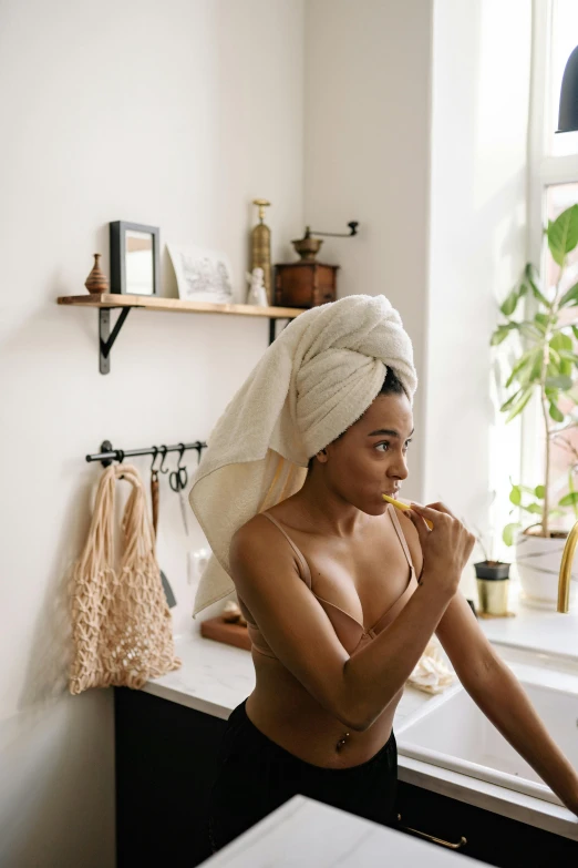 a woman standing in a bathroom with a towel on her head, by Julia Pishtar, trending on pexels, renaissance, with brown skin, blowing hair, morning, vanilla