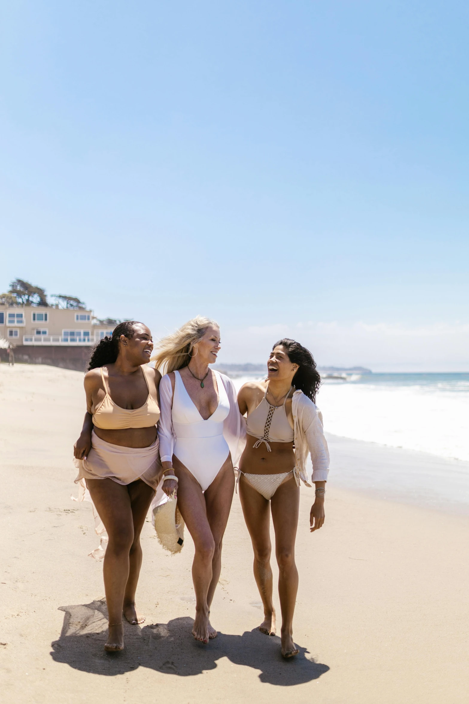 a group of women walking down a beach next to the ocean, swim suite, cream, los angeles, profile image