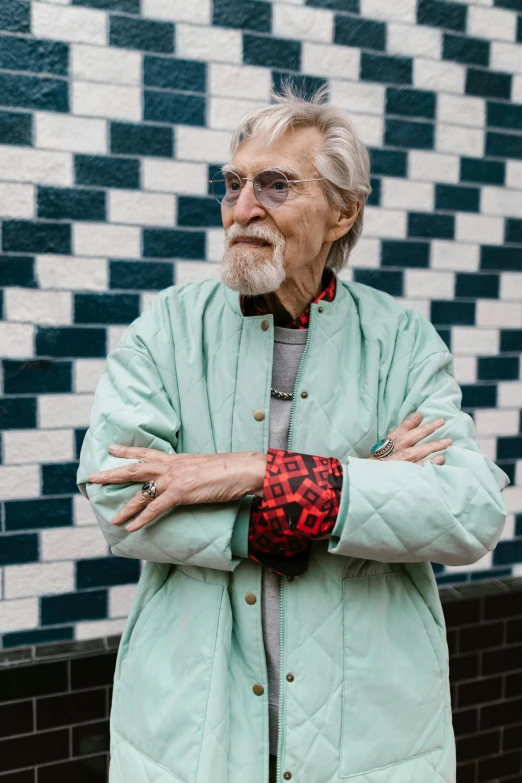 a man standing in front of a brick wall, long white hair and beard, brightly coloured, barry chuckle, looking off into the distance