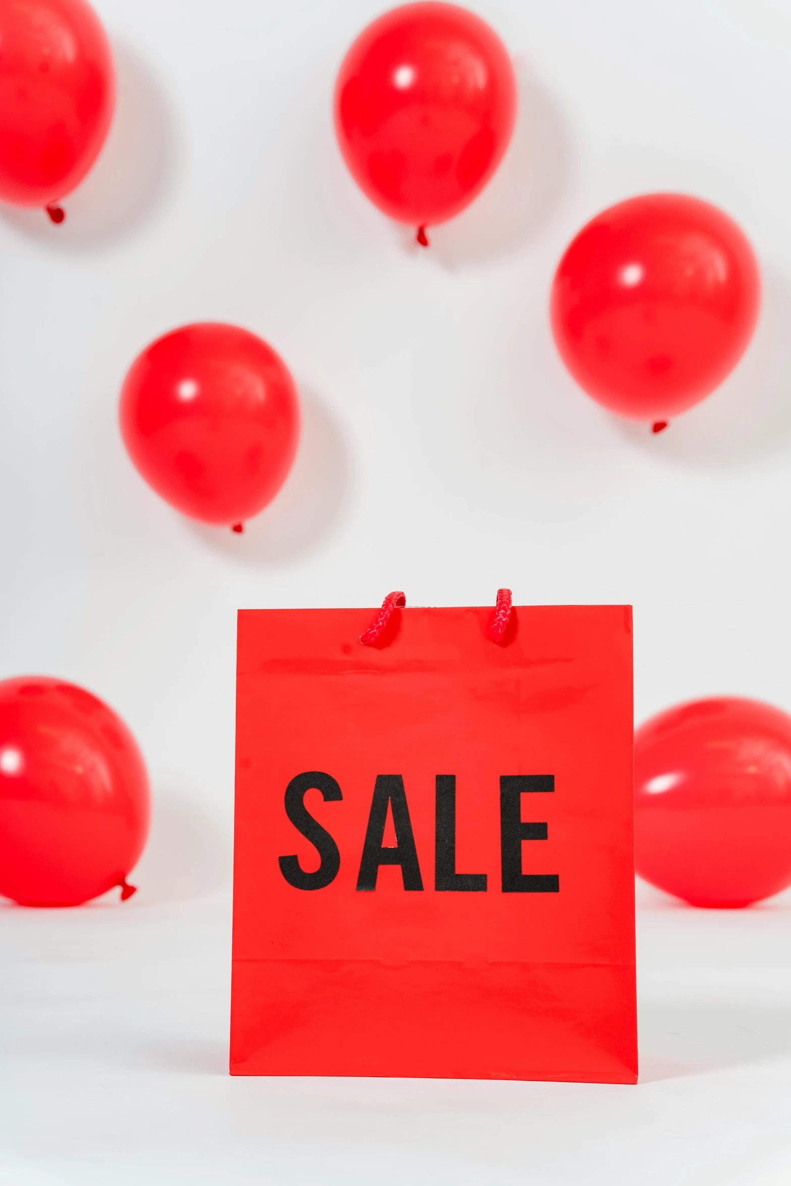 a red sale sign surrounded by red balloons, by Julia Pishtar, curated collections, bags, high quality image, tall