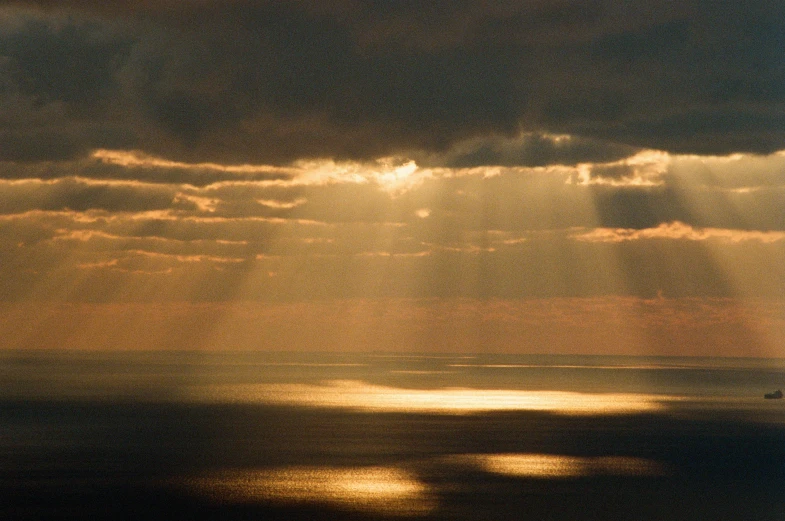 a large body of water under a cloudy sky, a picture, unsplash contest winner, light and space, gold dappled light, holy rays, 2000s photo, looking out over the sea